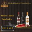A premium banner for Khukri Limited Cask Series rum featuring three bottles—Himalayan Gold, Dark Rum, and White Rum—on a dark wooden table against a background of aged oak barrels.